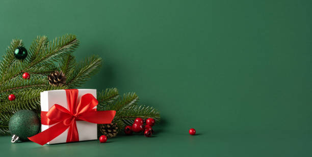 istock A beautifully wrapped Christmas gift with a red bow sits among pine branches, red berries, and ornaments, capturing the essence of holiday spirit and winter celebrations 2187102154
