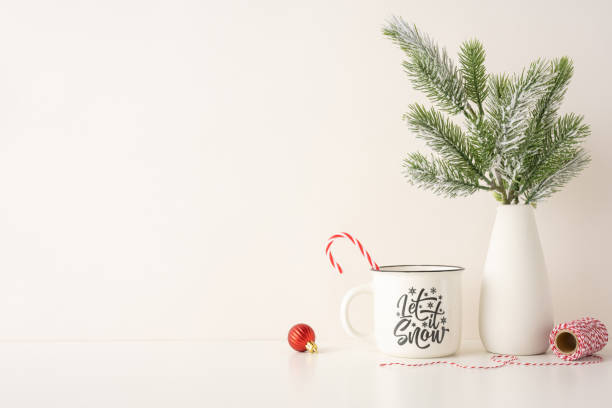 istock A side view cozy and minimalist Christmas setting featuring a festive mug with candy canes, pine branches in a vase, and holiday decorations on a white background 2187102166