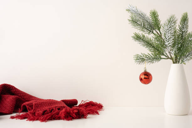istock A side view simple scandinavian style setup featuring a red ornament hanging on pine branches in a white vase. Cozy red knit fabric adds warmth to the minimalistic holiday decor 2187102172