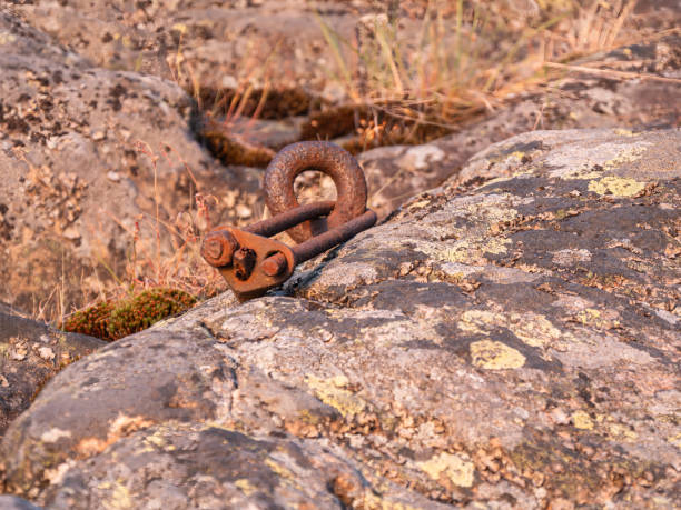 A rusty metallic ring fixture embedded in a weathered rock, surrounded by mos