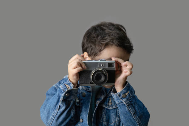 istock Cute little boy holding camera in hands and taking pictures 2187102934