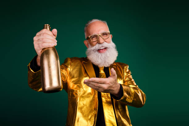 istock Charismatic elderly man celebrating in style with a golden bottle, dressed in a suit, capturing festive elegance against a green backdrop. 2187103634