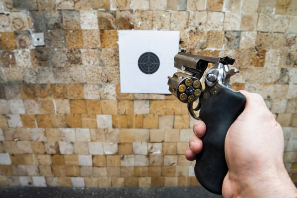 Human hand holding a revolver handgun against a bright light flare background. Concept of gun violence