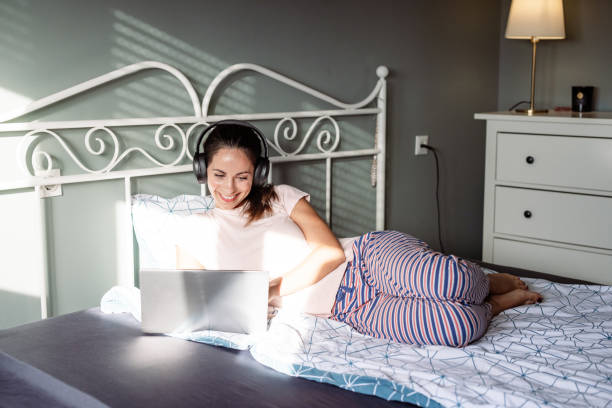 istock Smiling woman relaxing in bed and using a laptop 2187106978