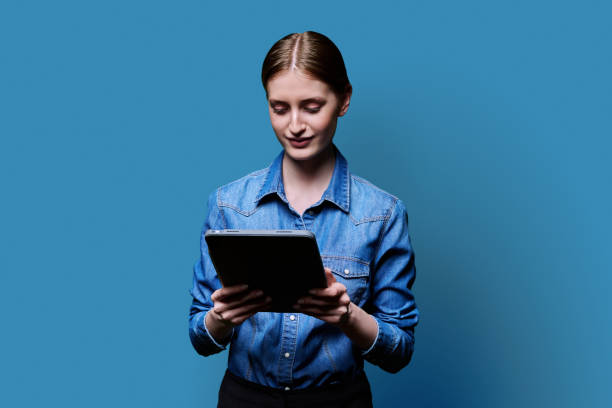 istock Teenager student girl with digital tablet on blue studio background 2187107763