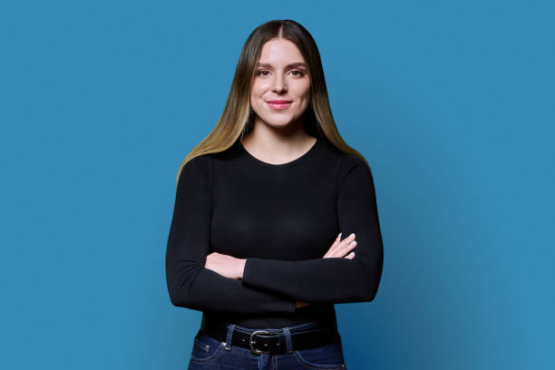 istock Young confident woman with crossed arms looking at camera on blue background 2187107879