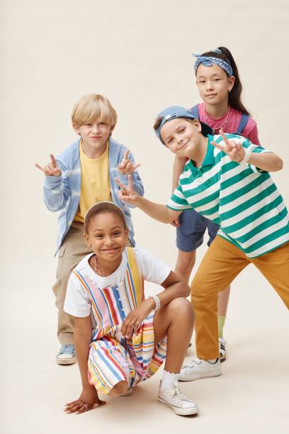 istock Multiethnic Group of Four Smiling Kids Showing Funny Gestures while Posing in Studio 2187109702