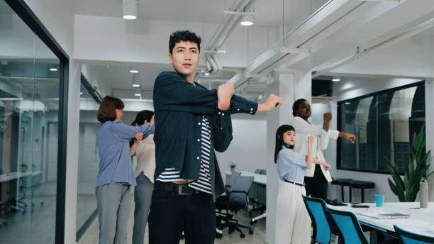 istock Workplace Wellness: Diverse Team Stretching and Collaborating in a Modern Office 2187112090