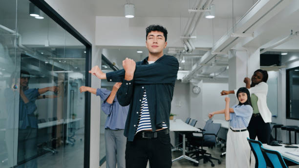 A diverse group of coworkers stretching together in a modern office, emphasizing wellness, teamwork, and a healthy work environment.