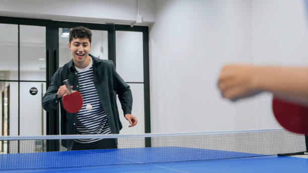 istock A young hispanic Latin man holding a paddle during a table tennis match in a modern office space with glass walls. Casual and fun workplace activity. 2187112227