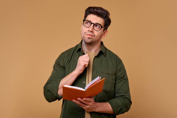 istock A focused man is intently analyzing his notes with a pen, thoroughly immersed in his crucial work 2187112308