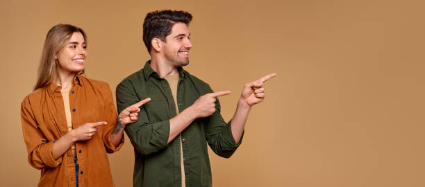istock An Excited Young Couple Pointing and Smiling Happily Against a Neutral Background Setting 2187112367
