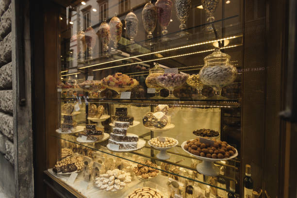 A charming display of colorful confections and delicate pastries in a Florence sweets shop. The shelves are filled with traditional Italian candies, ranging from colorful sugar-coated sweets to beautifully arranged chocolate truffles. Ornate glass jars filled with jelly beans and delicate cookies offer a feast for the eyes as well as the taste buds. The fine detail and careful arrangement of these desserts reflect the art of Italian craftsmanship, creating an irresistible scene for anyone walking by the shopfront.