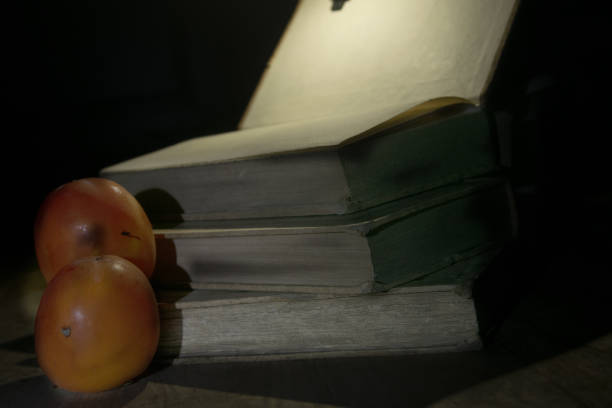food and culture concept with old books and two fruits in chiaro scuro