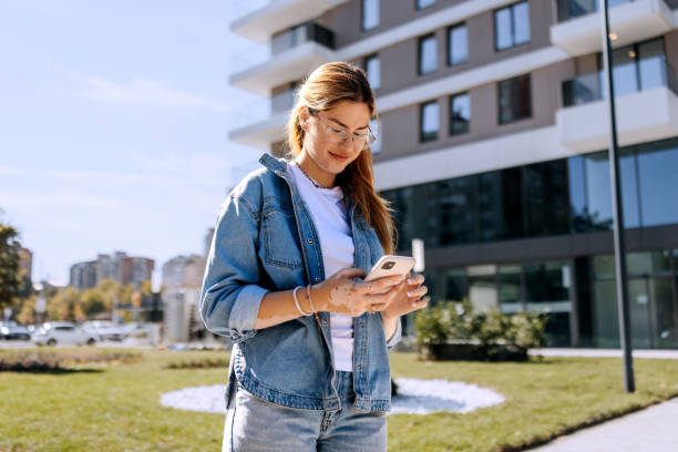 istock Young casually clothed woman using smart phone outdoors 2187118517