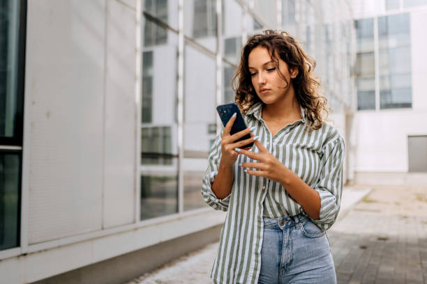 istock Casually clothed beautiful woman using smart phone outdoors 2187118956