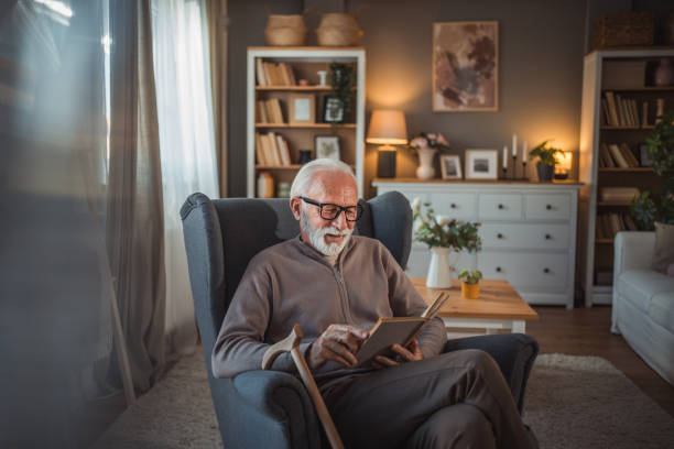 istock An elderly man reads a book at home while relaxing in his comfortable armchair 2187119216