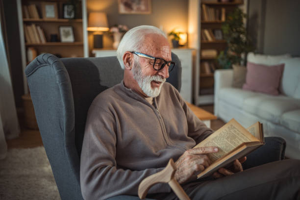 istock An elderly man reads a book at home while relaxing in his comfortable armchair 2187119233