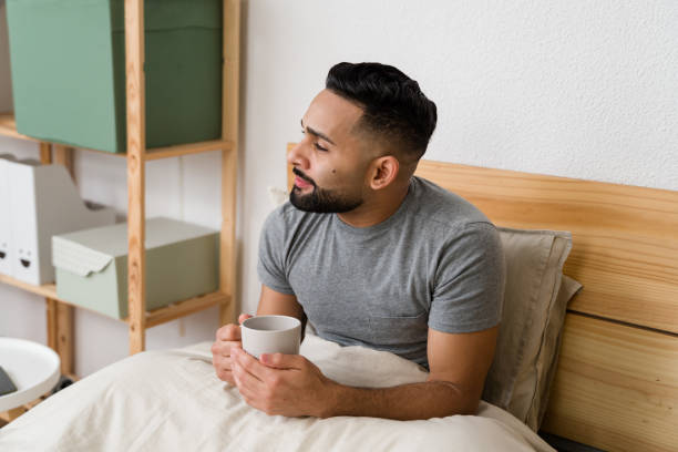istock Young man waking up and drinking coffee in bed 2187120222