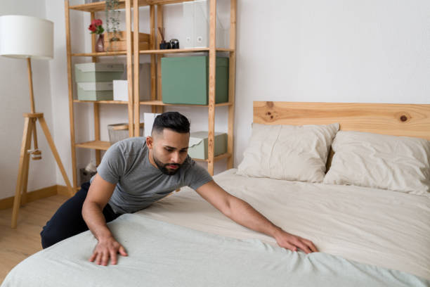istock Young man making bed in modern bedroom 2187120427