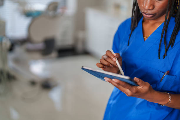 istock Close up to healthcare worker with blue scrubs hands using digital tablet. 2187120611
