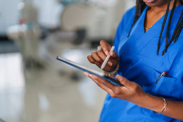 istock Close up to healthcare worker with blue scrubs hands using digital tablet. 2187120675