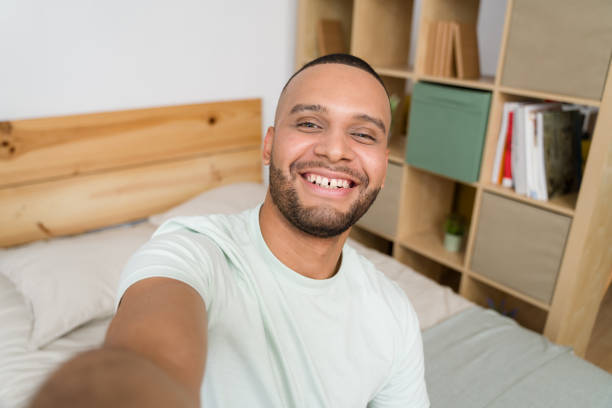 istock Young man taking a selfie on bed smiling at camera 2187120891