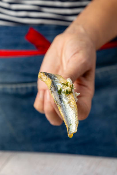 istock Hand holding sardine with herbs and garlic, close-up view 2187124800