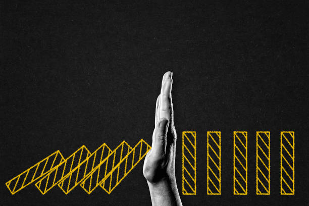 Hand Stopping Domino Blocks in  Black and White on Textured Paper Background, Copy Space. Business Crisis Effect Concept