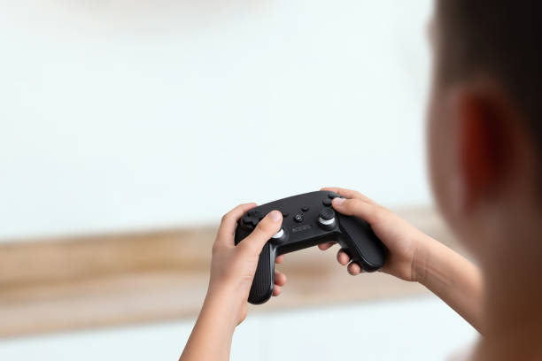 istock Over the shoulder view of a boy holding a gamepad, clean background with empty space for text, perfect for gaming promotions and creative advertising 2187127792