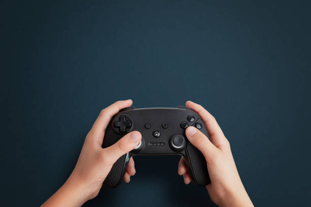 istock Top view of a hand holding a gamepad on a blue desk, flat lay composition with clean space for promotional text, ideal for gaming and tech branding 2187127793