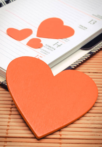 Blank open notebook and red heart on blackboard