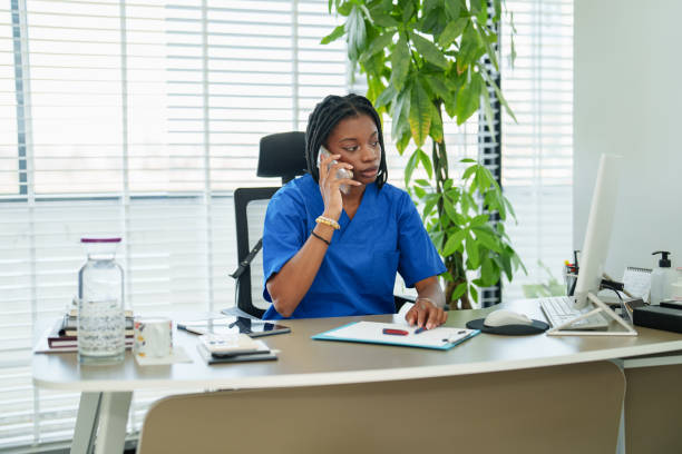 istock Woman with blue scrubs working on computer and talking on phone. 2187130783