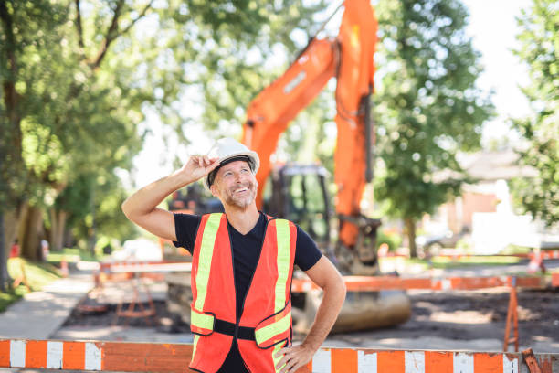 istock caucasian engineer with white helmet at work and having a mechanical shovel on the back 2187131333