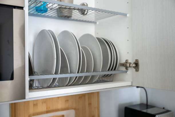 istock Stacked white plates in a kitchen cabinet with a metal rack, against a light interior background. Concept of kitchen organization 2187131683