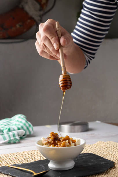 istock Hand drizzling honey over bowl of nuts and yogurt. 2187131787
