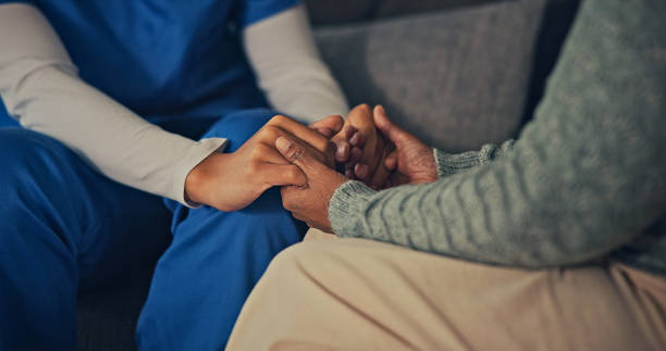 Female nurse doctor wearing uniform holding hand of senior grandmother patient help express empathy encourage tell diagnosis at medical visit, older people healthcare support concept, close up view.