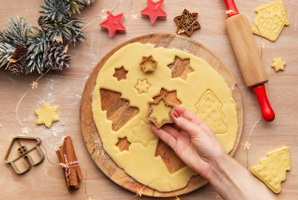 istock Woman making christmas cookies using star shaped cutters on wooden board 2187141981