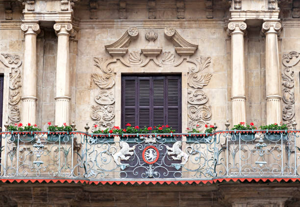 Intricate balcony railing adorned with flowers and carvings on a stone facade.