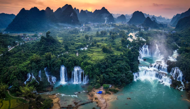 istock Sunset over mountain range with Ban Gioc waterfall flowing in tropical rainforest at Vietnam 2187142735