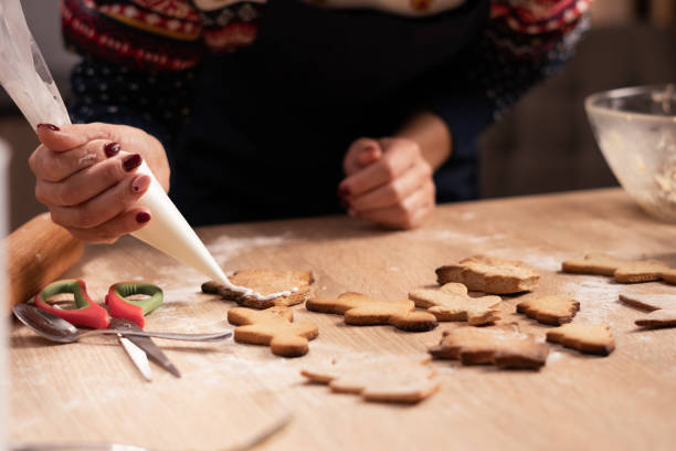 istock Woman decorating Christmas gingerbread cookies with icing 2187142933