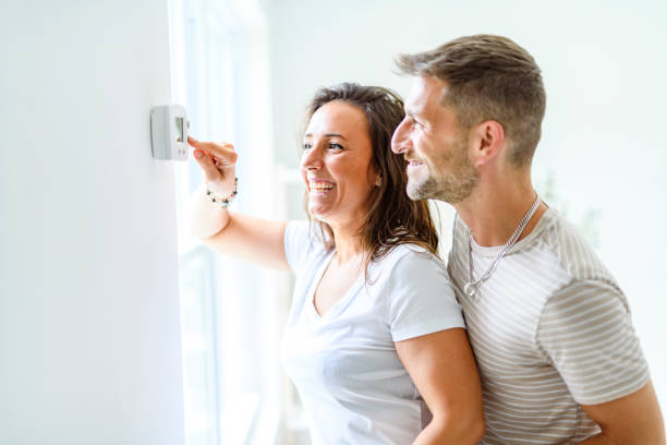 istock Smiling couple Adjusting Thermostat On Home Heating System 2187142986