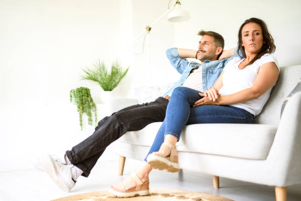 istock Beautiful couple is having a quarrel while sitting on sofa at home 2187143128