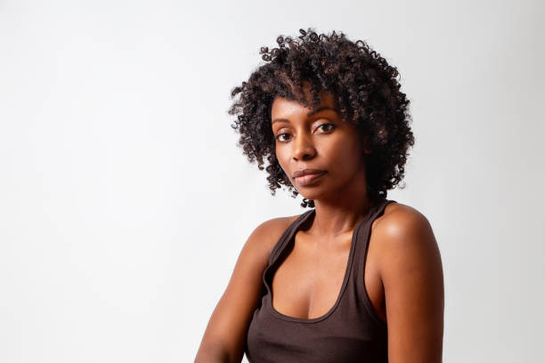 Black woman portrait on white background, studio shot. Brown tank top