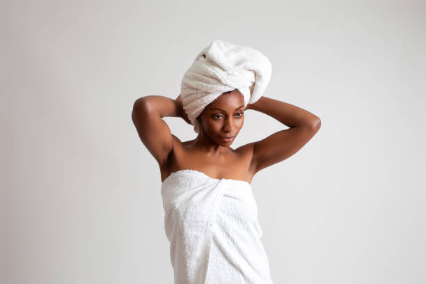 Black woman wrapped in a bath towel on a white seamless background. studio shot