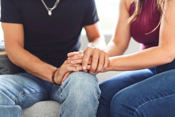 istock Hand in hand through it all. Shot of an unrecognizable couple holding hands while sitting on a sofa at home. 2187144943