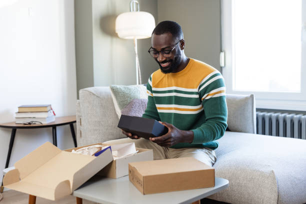 istock Man smiling while unboxing a package in his living room 2187145828