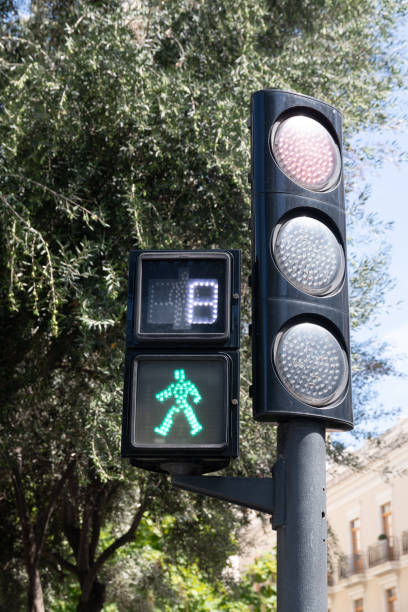 Green pedestrian traffic light showing walking figure with blue sky
