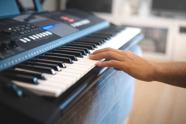 istock Close-up of hands playing a digital keyboard under warm natural light, capturing the essence of creativity, focus, and musical passion in an intimate indoor setting 2187148086