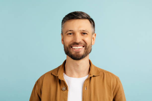 istock Portrait of middle aged smiling bearded man looking at camera isolated on blue background. Confident modern hipster with stylish hair after barbershop service 2187149384